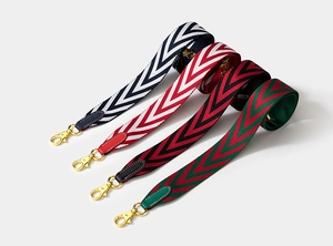 Detail of four multi-color chevron woven bag straps with leather ends and gold metal clips
