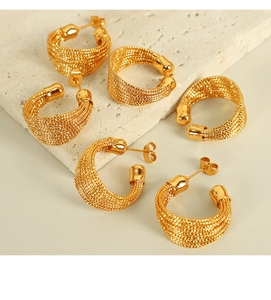 Detailansicht der luxuriösen goldfarbenen geflochtenen Creolen und Earcuffs auf Stein