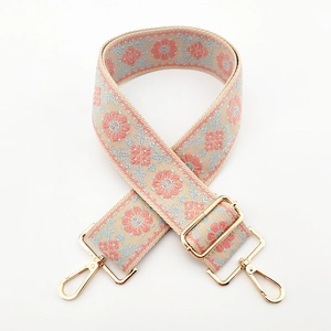 Detail of adjustable ethnic jacquard strap with gold metal hooks and floral pattern
