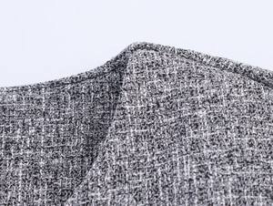 Close-up of the grey tweed woven fabric showing detailed texture and yarn patterns
