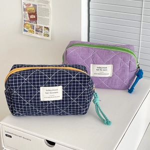 Close-up of quilted plaid pouches with colorful zippers and woven rope pullers