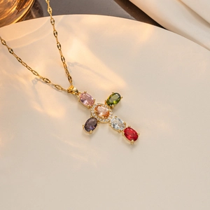 Detailed macro of a gold-plated cross necklace featuring multi-colored micro-set zircons