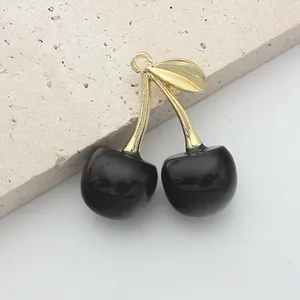 Detailed view of cherry pendants with black resin fruits and gold alloy leaf for DIY jewelry