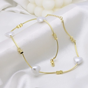 Detail of gold necklace featuring white heart pearls and geometric metal beads on silk