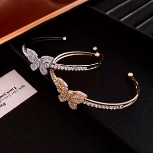 Detail of gold and silver butterfly open bracelets with pavé zircons in a black velvet box