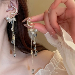 Détail de boucles d'oreilles lune dorées avec franges en cristal et perles grises