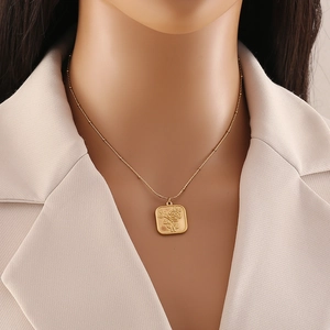 Detailed close-up of a golden tarot-style pendant with embossed rose worn on a model
