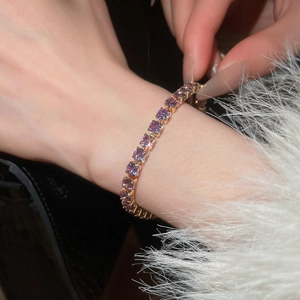 Close-up of elegant rose gold tennis bracelet featuring round-cut purple zircon stones