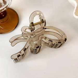 Detailed close-up of a translucent brown butterfly hair claw with a gold metal spring
