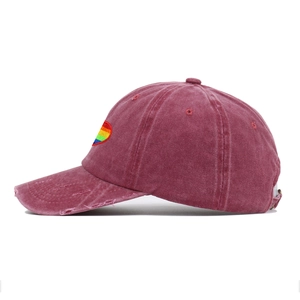 Detail of rainbow heart embroidery and distressed ripped brim on a burgundy cotton cap