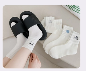 Detail weißer Baumwollsocken mit Stickerei und Seitenetikett auf minimalistischem Grund