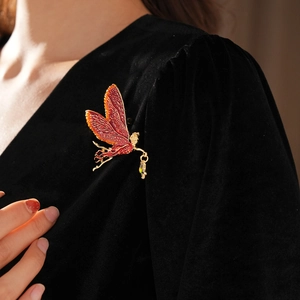 Detailed macro view of vintage fairy brooch with enamel wings on black velvet fabric