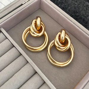 Vue rapprochée de boucles d'oreilles nœuds dorés sur un coffret à bijoux en velours violet