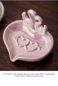 Macro shot of pearl glazed heart ceramic tray with double swan decor on wood surface