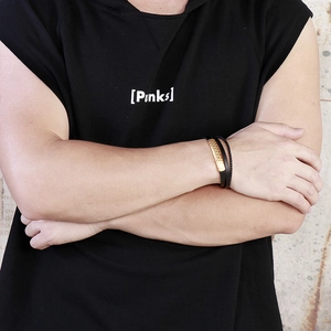 Detail shot of men's braided black leather bracelet with gold metal clasp on model