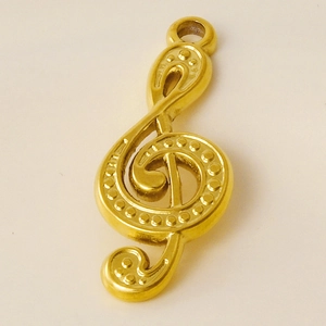 Macro shot of gold musical note pendant with dotted texture on stainless steel