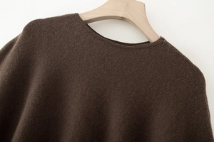 Detailaufnahme des Rundhalsausschnitts und der feinen Stricktextur des dunkelbraunen Ponchos