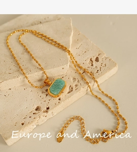 Detail of gold stainless steel necklace with green amazonite stone on stone background