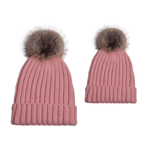 Close-up of pink parent-child ribbed knit beanies with fluffy faux fur pom-poms