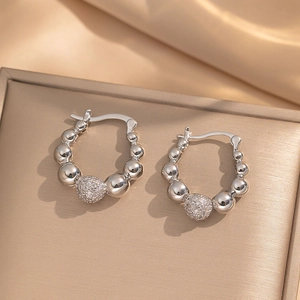 Minimalist silver steel bead earrings featuring a sparkling pavé sphere on silk background