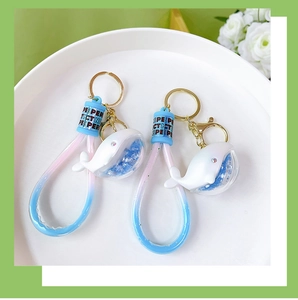 Detail of white whale keychain with blue liquid glitter and colorful silicone strap