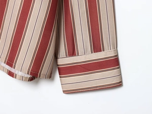 Détail macro du poignet de chemise à rayures rouges et beige avec texture de couture