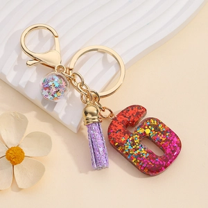 Macro shot of resin number 6 keychain with red glitter, purple tassel, and star sequin ball