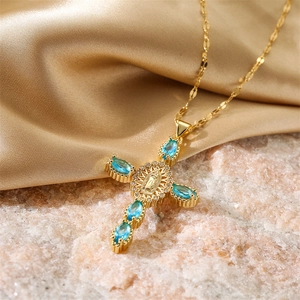 Détail de collier croix dorée avec pierres marquises bleues et relief de la Vierge Marie