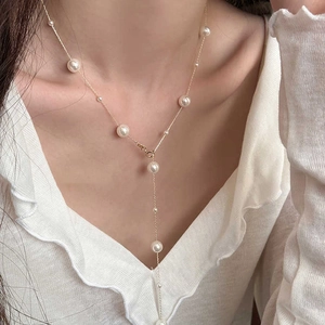 Elegant gold Y-shaped pearl necklace with dangling droplets on a model's collarbone