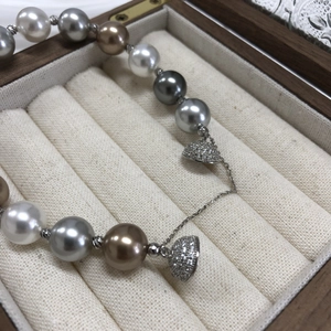 Macro detail of mixed color pearls with sparkling diamond-encrusted heart pendants