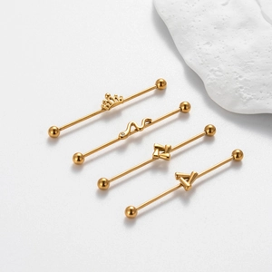 Detail of four golden stainless steel industrial piercings with crown and snake designs