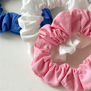 Macro shot of blue, white, and pink cotton scrunchies with elastic pleated fabric details