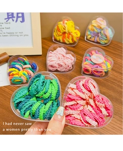 Macro detail of high-elasticity ruffled hair ties in colorful heart-shaped gift boxes