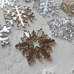 Close-up of gold and silver acrylic snowflake cake decorations with mirror finish