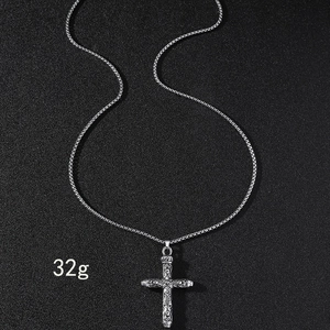 Vue détaillée d'un pendentif croix en acier inoxydable argenté avec des motifs en relief précis