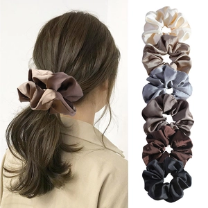 Detail view of six silk satin scrunchies in neutral tones shown on model and in a stack