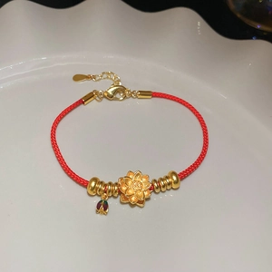 Détail du bracelet en corde tressée rouge avec lotus doré et petit pendentif en émail