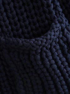 Detailed macro view of navy blue chunky knit texture and pocket edge on a cardigan