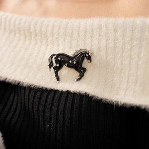 Close-up of vintage black enamel horse brooch with sparkling rhinestones on fabric