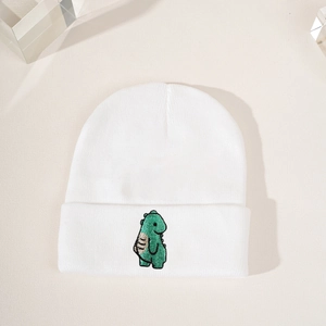 Weiße gerippte Strickmütze mit süßer grüner Dino-Stickerei in einer stylischen Draufsicht