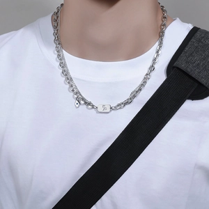 Men's double layer silver necklace with rectangular pendant and blue eye charm on model