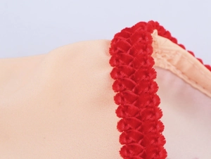 Detailed macro view of soft red chenille trim stitched on beige tropical dress fabric
