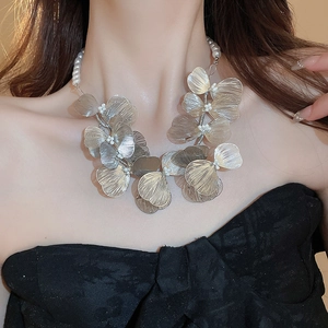 Macro detail of a silver metal woven flower necklace with elegant pearl accents