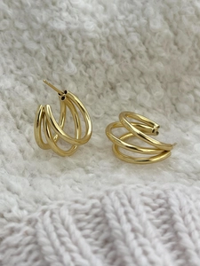 Detail of gold layered hoop earrings with triple overlapping rings on knit background