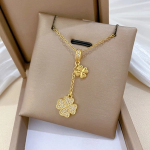 Detailed close-up of double clover pendant necklace with sparkling white crystals in a gift box