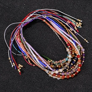 Detailopname van handgemaakte 2mm kralenarmbanden met gefacetteerde steen en gevlochten koord