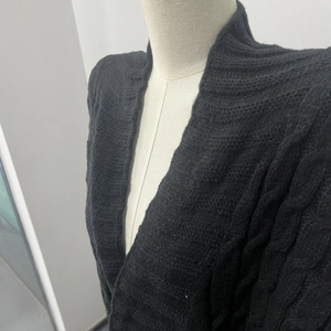 Dettaglio macro del cardigan nero a maglia intrecciata con trama in rilievo