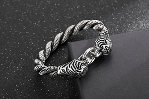 Detailed close-up of punk style tiger head clasps and braided steel mesh bracelet