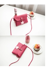 Detail of rose red mini crossbody bag with star pendant and sleek faux leather texture