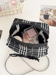 Vue détaillée de la trousse à damier avec nœud noir montrant le rangement interne